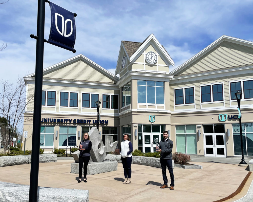 Stephanie Beck, VP of Marketing and Community Development, Renee Ouellette, President & CEO, and Michael Connors, Senior Marketing Specialist, pose with the two Diamond Awards in the plaza of UCU's Orono headquarters.